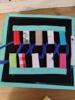 Jucărie educativă pentru copii cu panglici și cordoane de diverse culori și materiale.